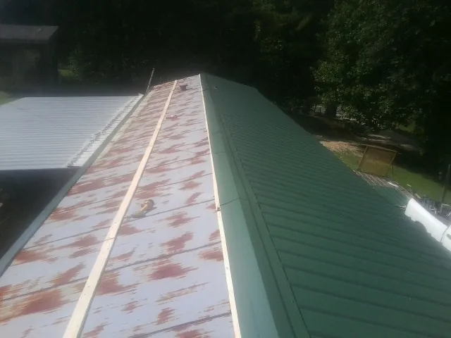 Old rusted panels beside newly installed green metal roofing — Wind Damage Roof Repair by Roofing Brothers in Twin Mountain