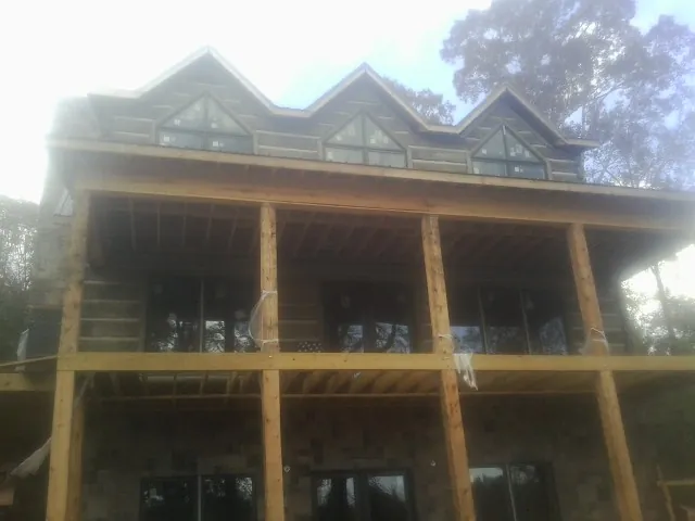 Dormers and porch framing on a large log home under construction — Roof Coating work by our crew in Twin Mountain