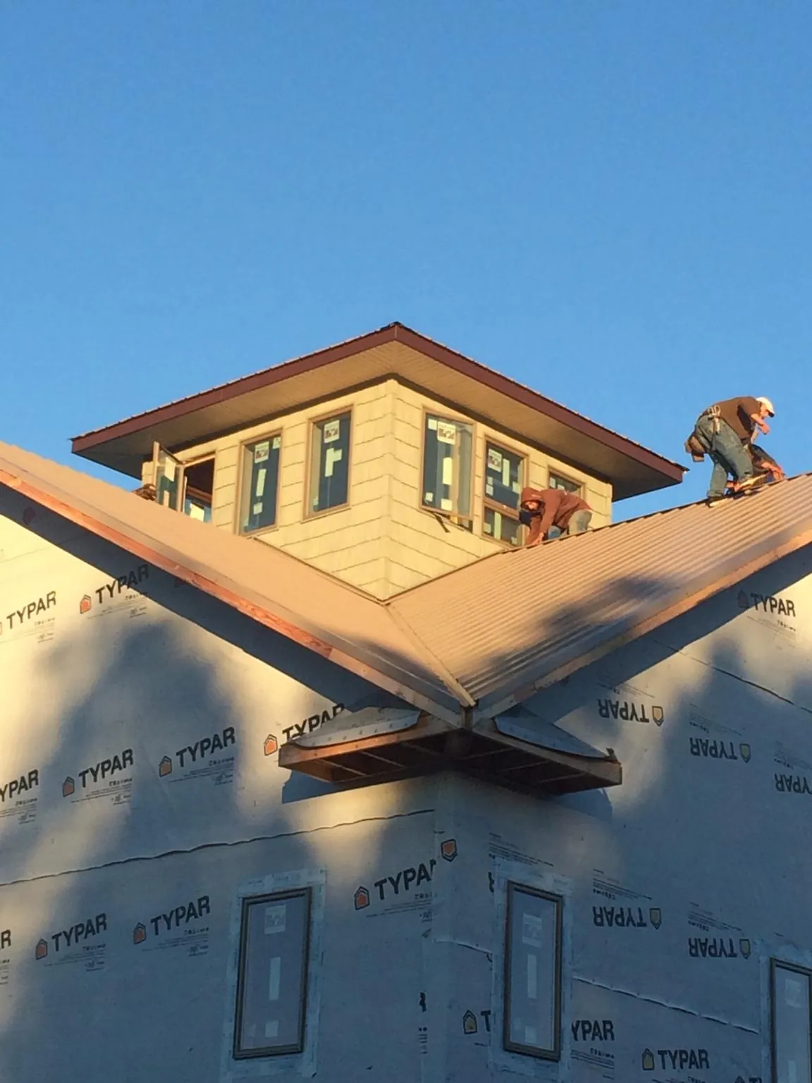 Roofers working around a rooftop cupola on a new metal roof at sunset — Roof Waterproofing in Twin Mountain by Roofing Brothers